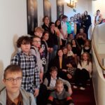 grupa uczniów stojąca na schodach i siedząca na schodach