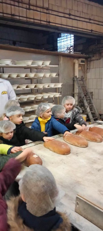 pięcioro uczniów dotyka wypieczony chleb, który właśnie wyszedł z pieca.