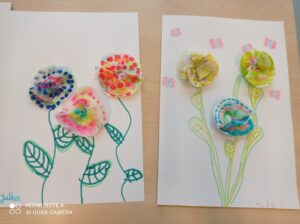 Praca plastyczna - kolorowe kwiaty naklejone na kartce papieru.