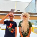Dwóch chłopaków jeden ubrany w czapkę i brodę św. Mikołaja.