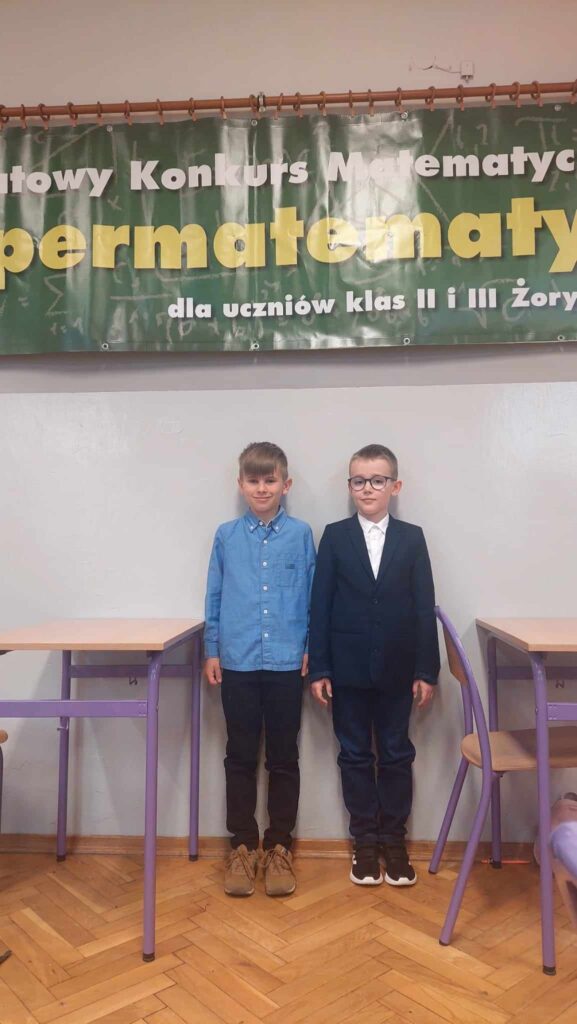 dwaj chłopcy stoją przy banerze Powiatowy konkurs matematyczny