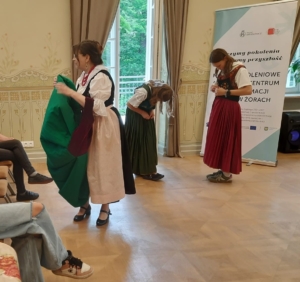 instruktorka tłumaczy uczestnikom zajęć o stroju śląskim